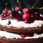 Close up of Black Forest Cake topped with fresh cherries and lashings of cream