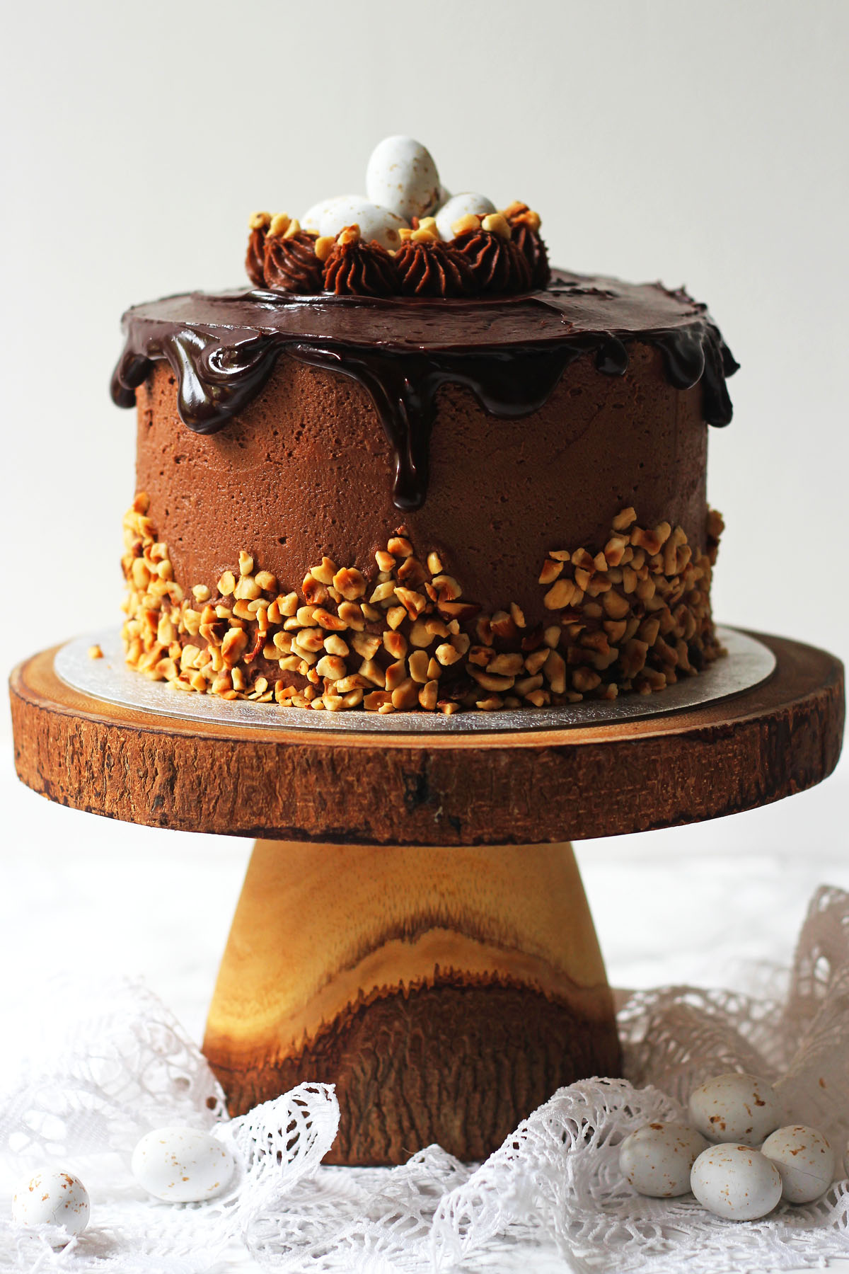 Nothing says Easter like a vanilla sponge cake smothered in Nutella buttercream, chopped hazelnuts, dark chocolate ganache, topped with praline Easter eggs! Get the recipe for this Praline Easter Cake at Supper in the Suburbs!