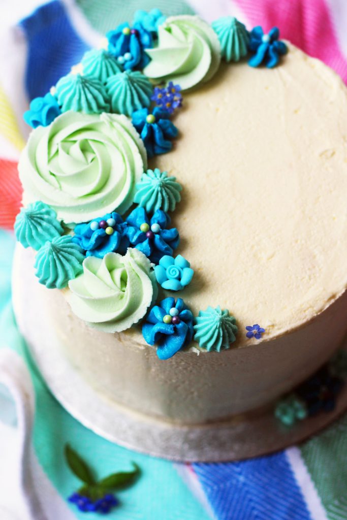 This stunning Lemon and Blueberry Layer Cake is the perfect spring celebration! Decorated with beautiful piped buttercream flowers and roses its a showstopping dessert. Get the recipe on Supper in the Suburbs!