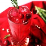 A long cocktail and cranberry juice and amaretto, garnished with fresh cranberries and rosemary