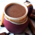 An earthenware mug of spiced hot chocolate spiked with cinnamon and amaretto.