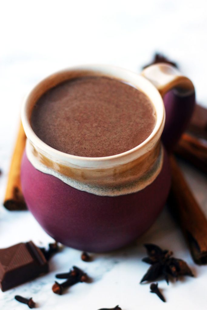 An earthenware mug of spiced hot chocolate spiked with cinnamon and amaretto.