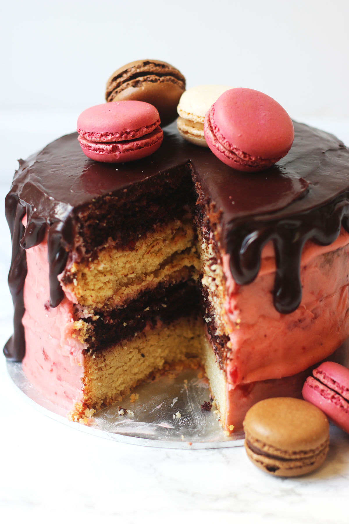 Neapolitan cake - layers of vanilla and chocolate sponge covered in real strawberry buttercream and chocolate ganache and topped with macarons