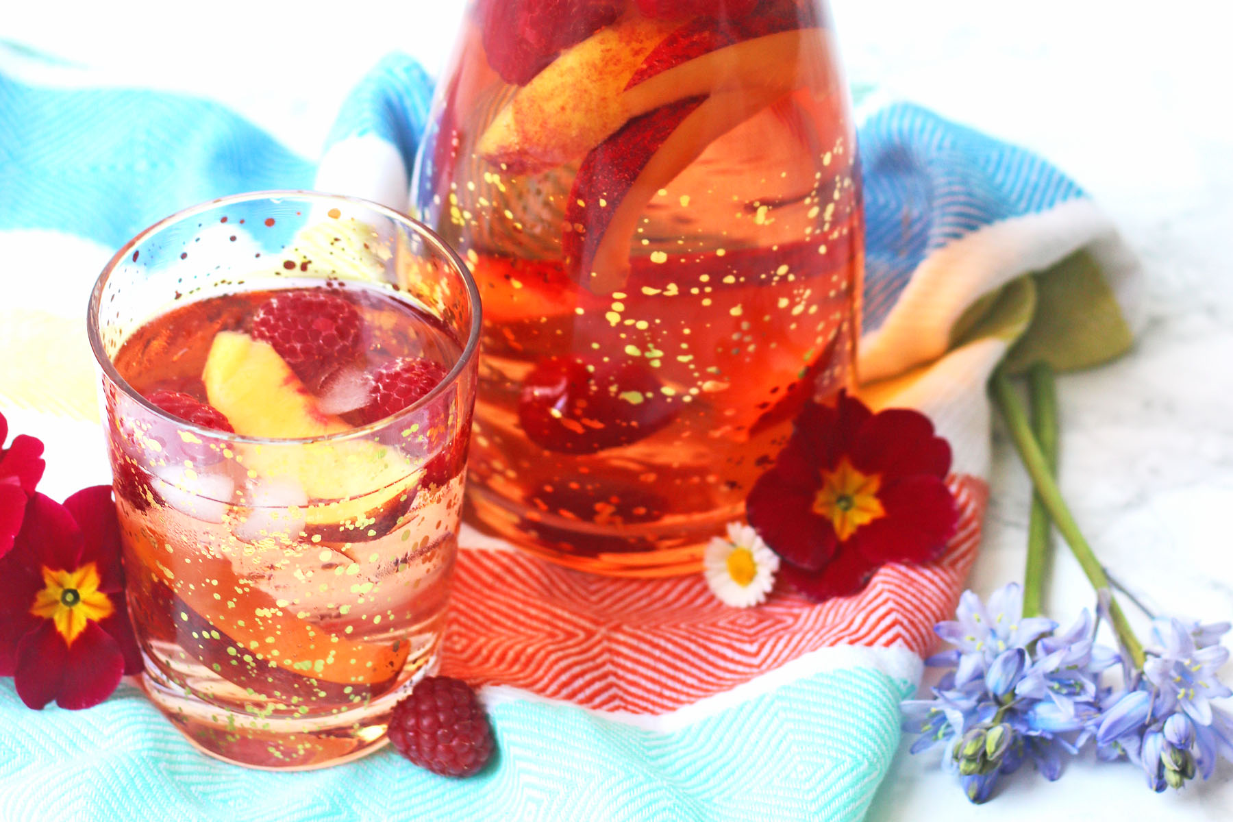 Glass of rose sangria, poured over raspberries and nectarine wedges
