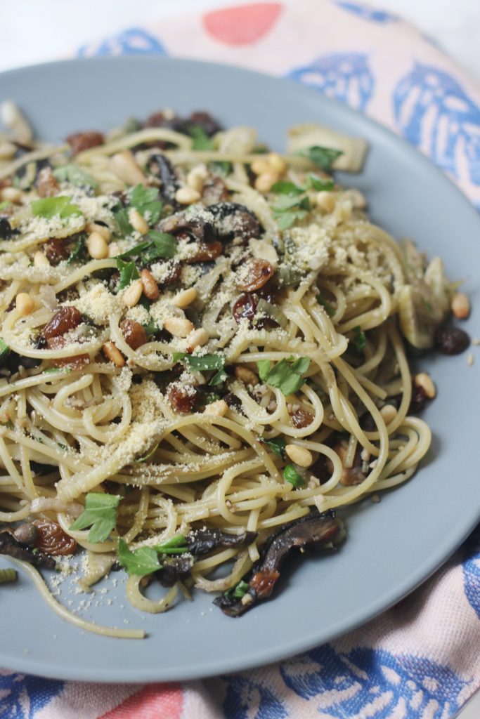 A plate of currant, caper and fennel spaghetti with a sprinkling of vegan parmesan
