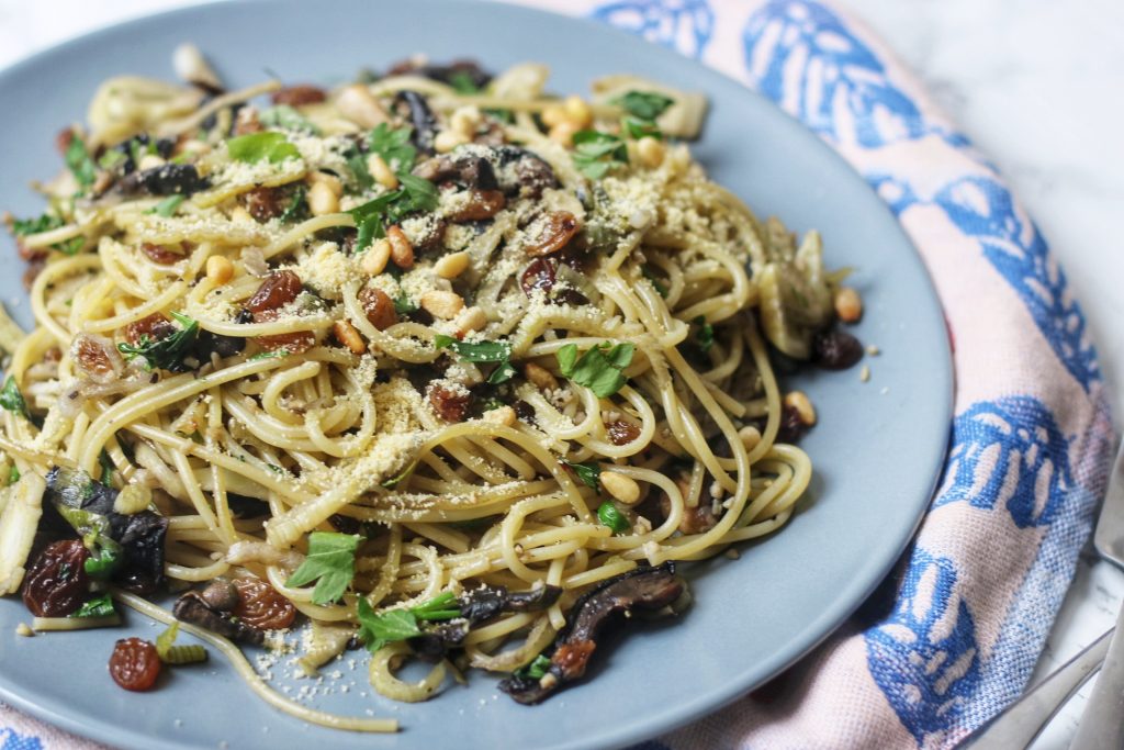 A plate of currant, caper and fennel spaghetti with a sprinkling of vegan parmesan