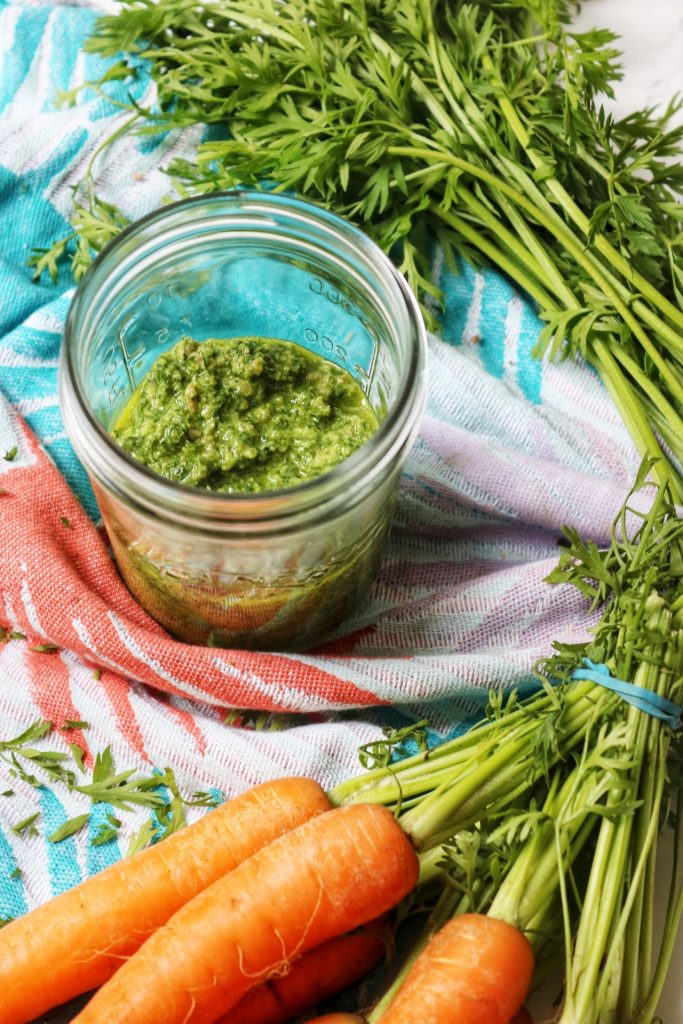 A jar of carrot top pesto with carrots