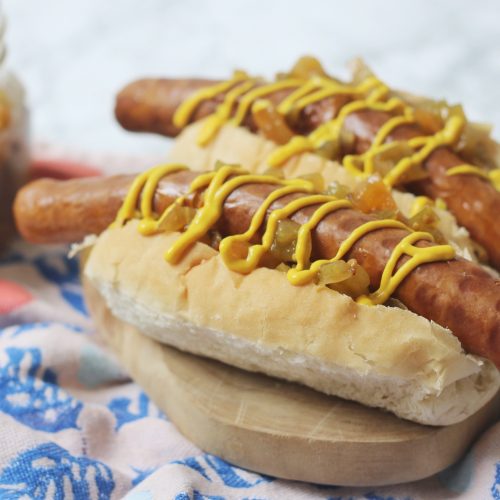 Vegan hot dogs topped with a drizzle of mustard and spoonfuls of green tomato hot dog relish!