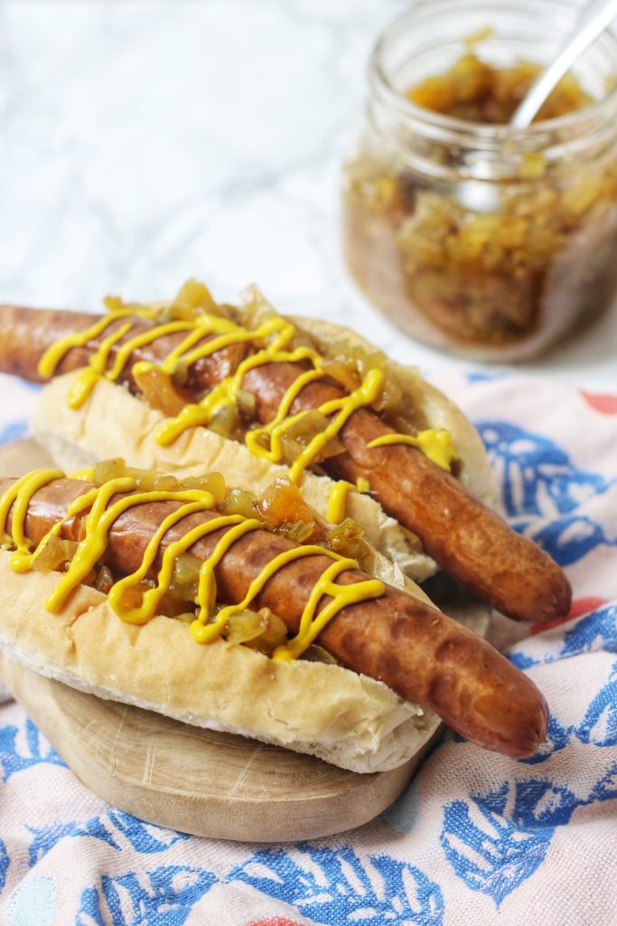 Vegan hot dogs topped with a drizzle of mustard and spoonfuls of green tomato hot dog relish!