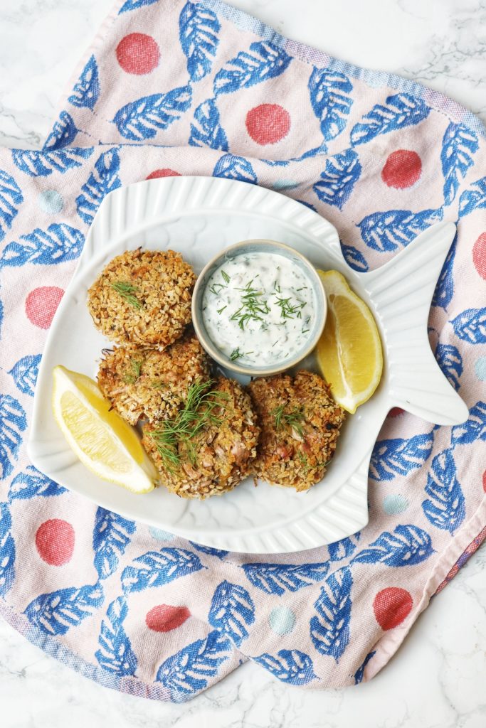 Overhead photo of vegan crab cakes and tartar sauce with lemon wedges