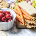 Vegan cheese served with pickled cherries, grapes, crackers and carrots