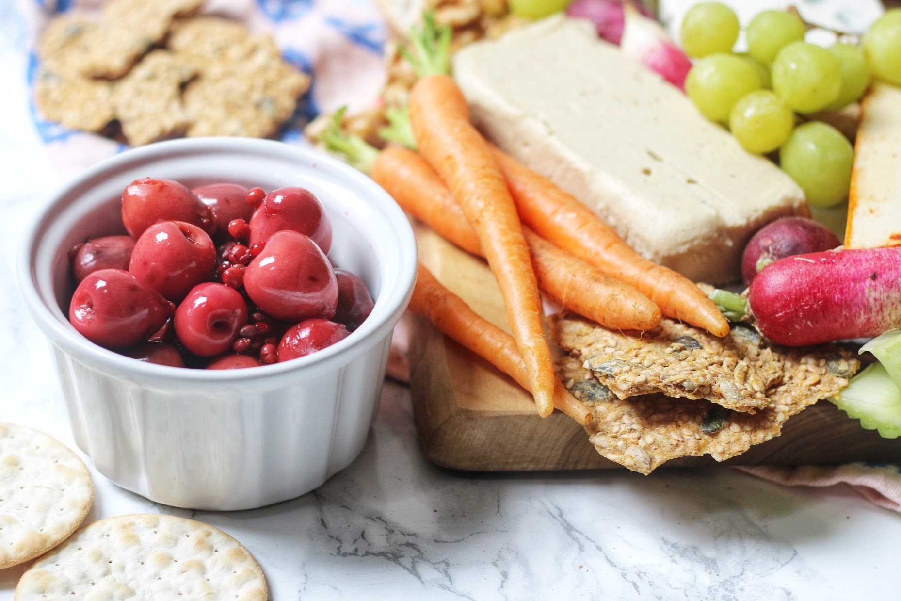 Vegan cheese served with pickled cherries, grapes, crackers and carrots