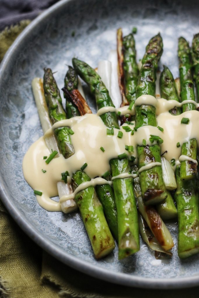 Silky smooth Vegan Hollandaise served over grilled asparagus and baby leeks