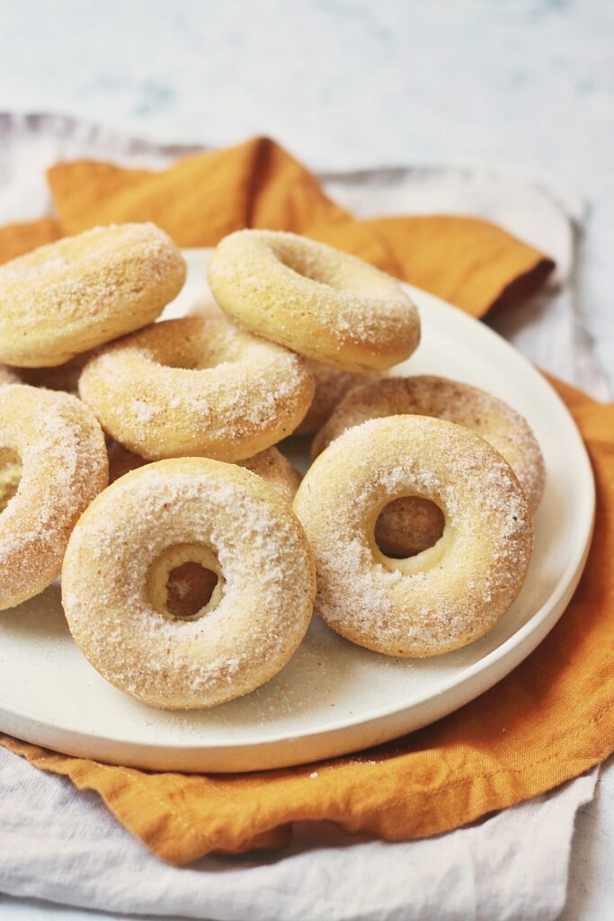 A plate of cinnamon baked doughnuts stacked on top of each other