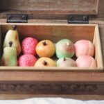 A wooden box filled with marzipan pears, strawberries, oranges, apples and peaches