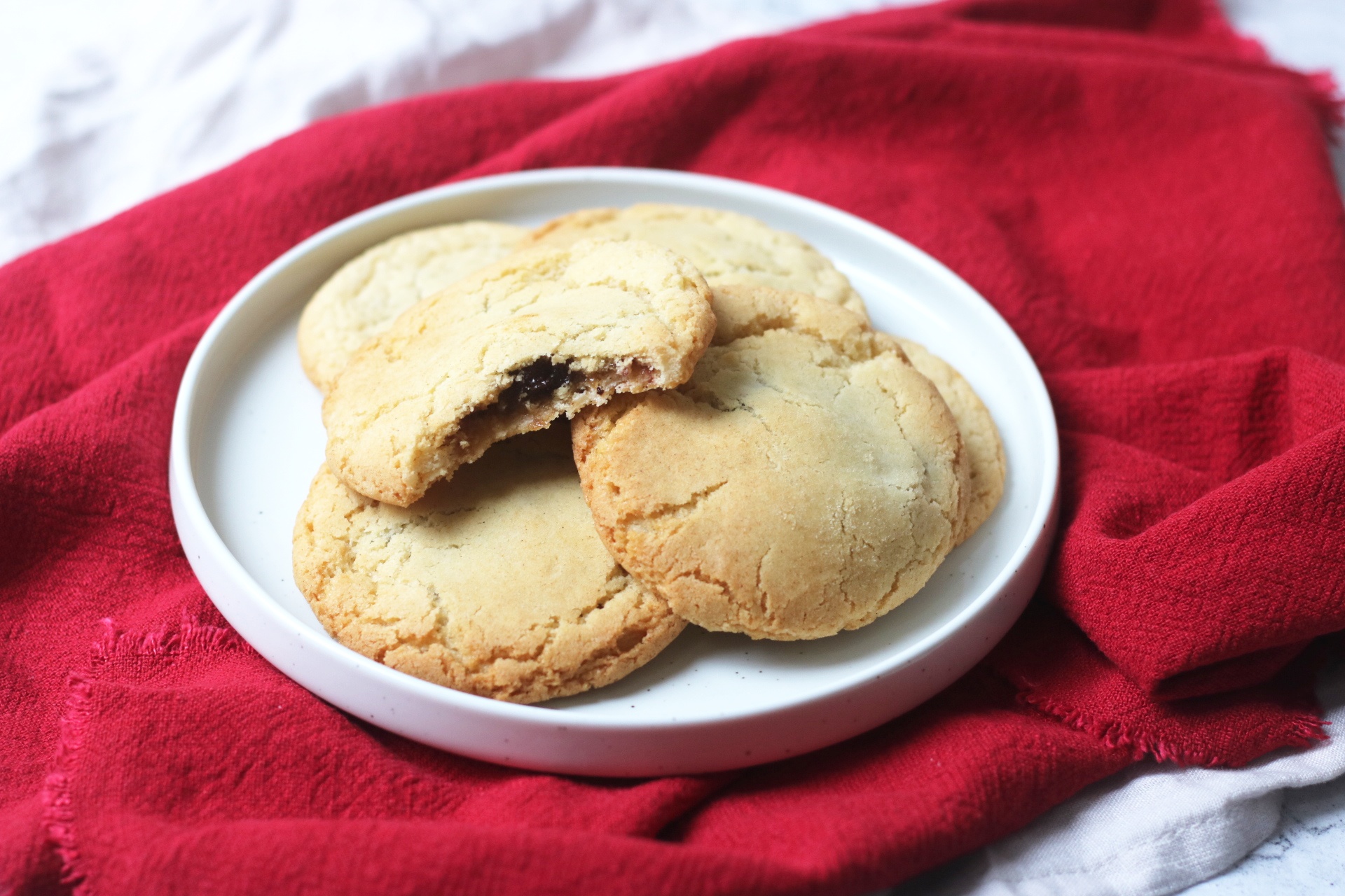 Vegan mince pie stuffed cookies on a plate with a bite taken out of one