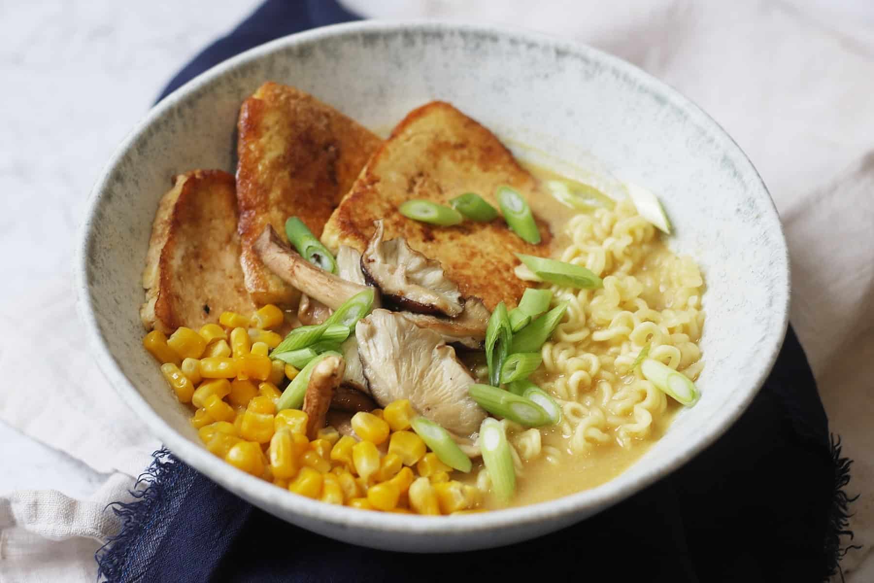 A bowl of Vegan Tonkotsu Ramen topped with smoked tofu, shitake mushrooms, sweetcorn and spring onions