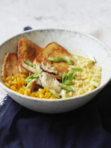 A bowl of Vegan Tonkotsu Ramen topped with smoked tofu, shitake mushrooms, sweetcorn and spring onions