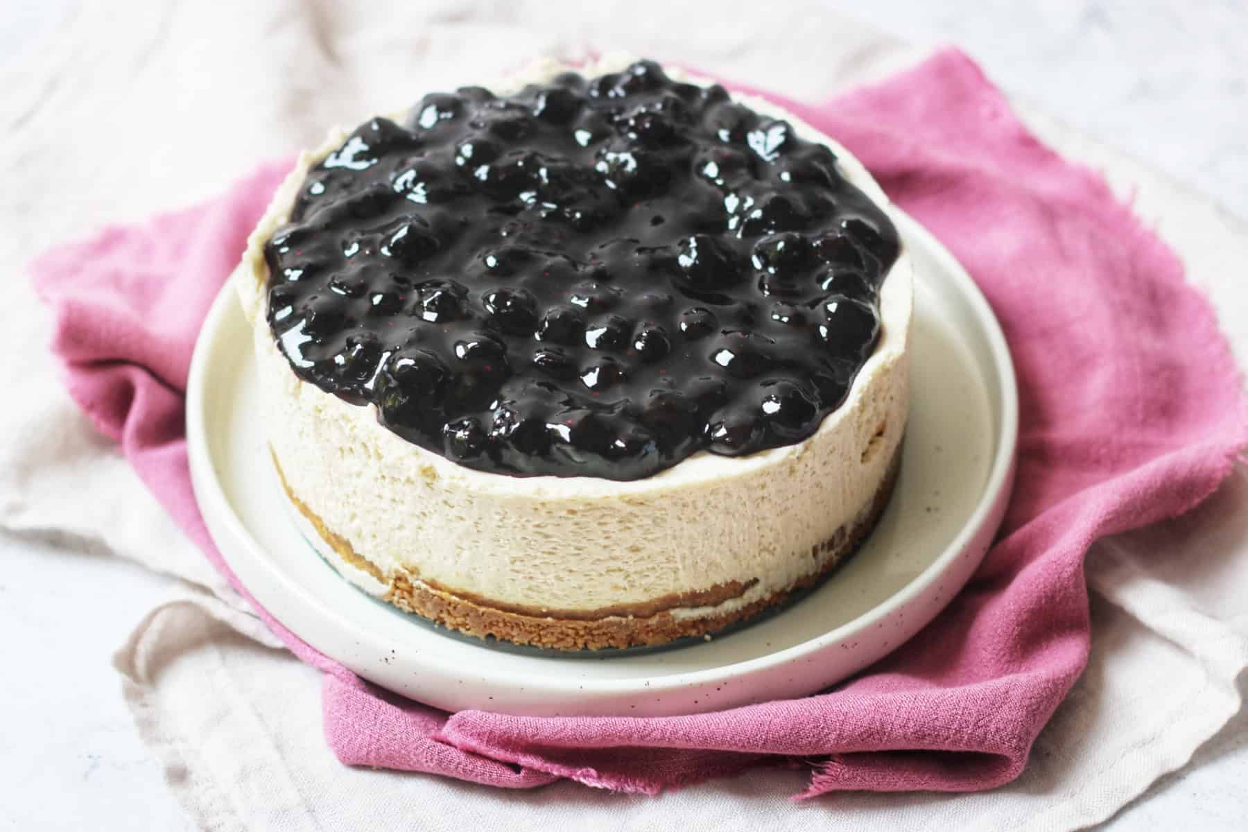 A whole vegan cheesecake topped with blueberry compote