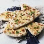 5 vegan naan breads stacked on top of a wire rack