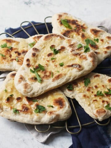 5 vegan naan breads stacked on top of a wire rack