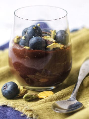 A vegan chocolate pot topped with blueberries and pistachios