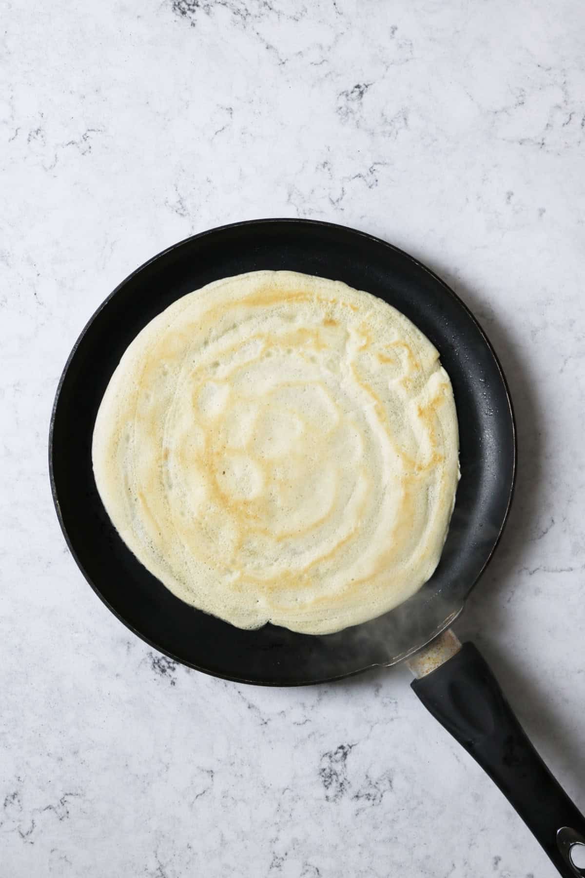 A cooked vegan crêpe in a crêpe pan