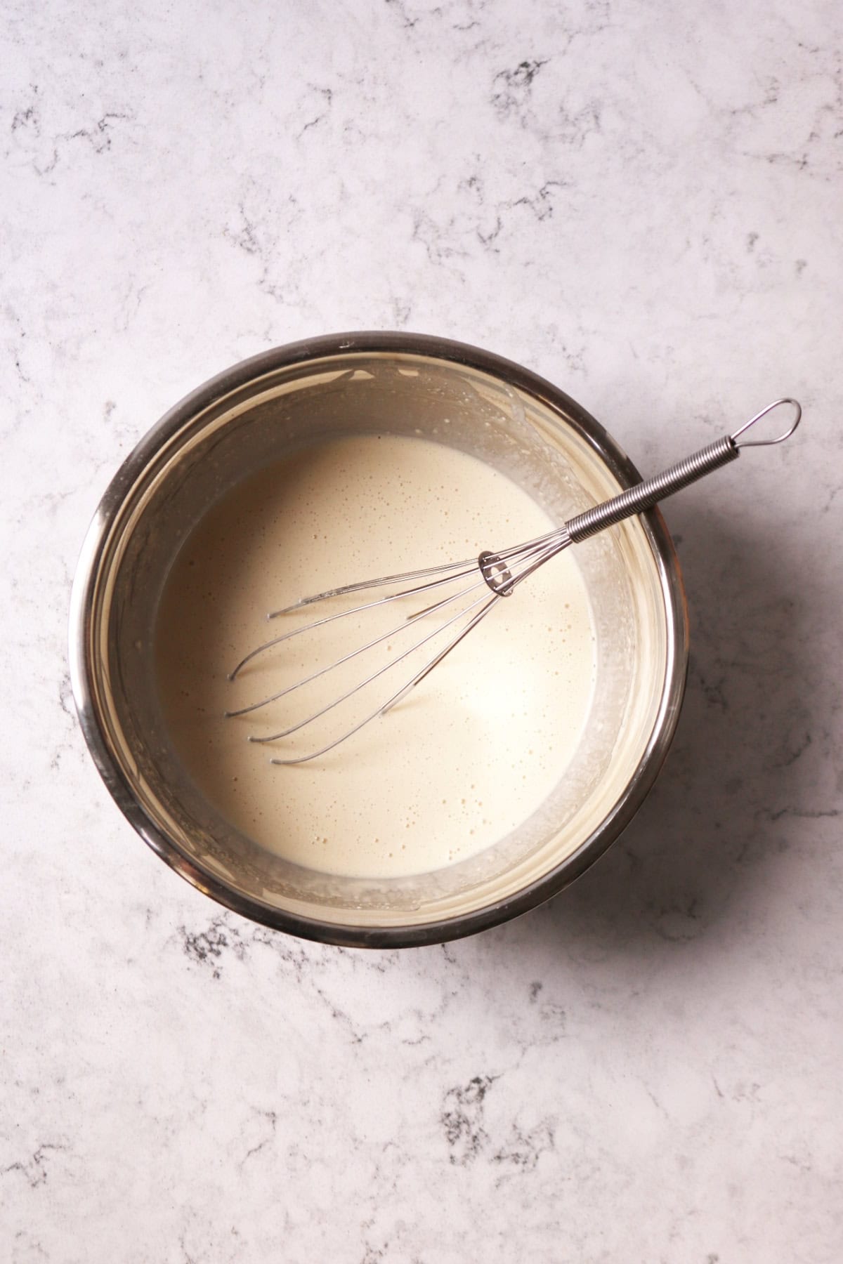 A bowl of vegan crêpe batter with a whisk in it