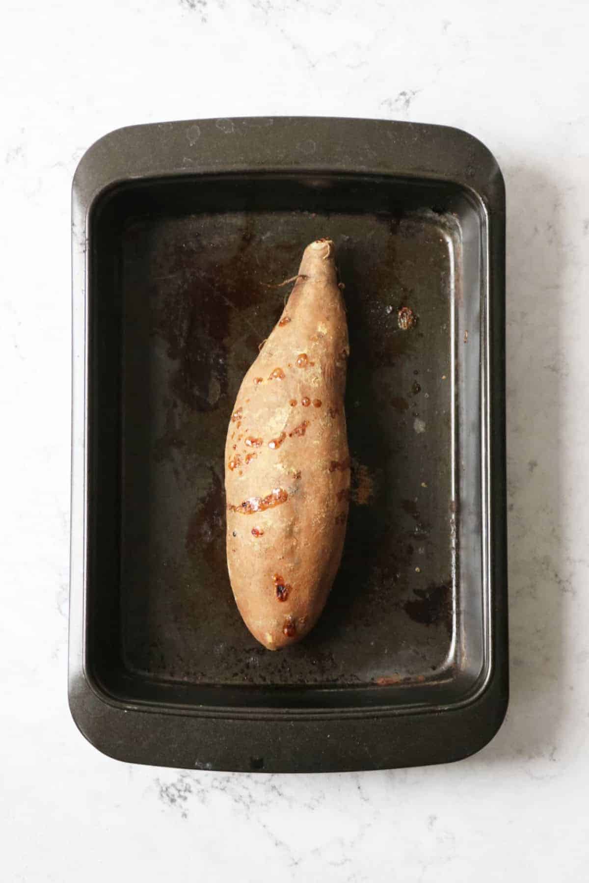 A large roasted sweet potato in a pan