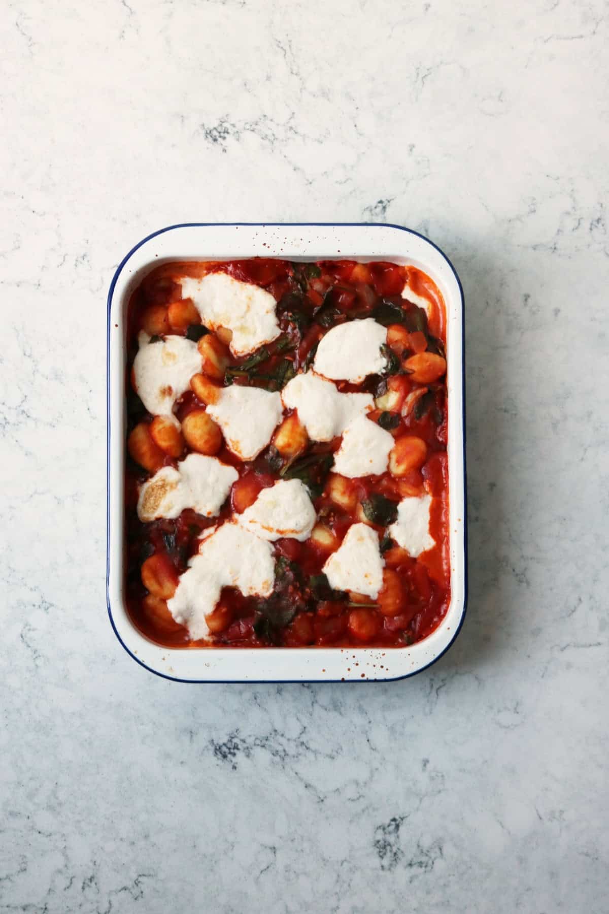 Vegan Baked Gnocchi with melted mozzarella in a white and blue oven dish