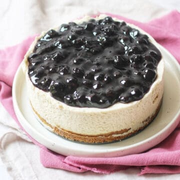 A whole vegan cheesecake topped with blueberry compote