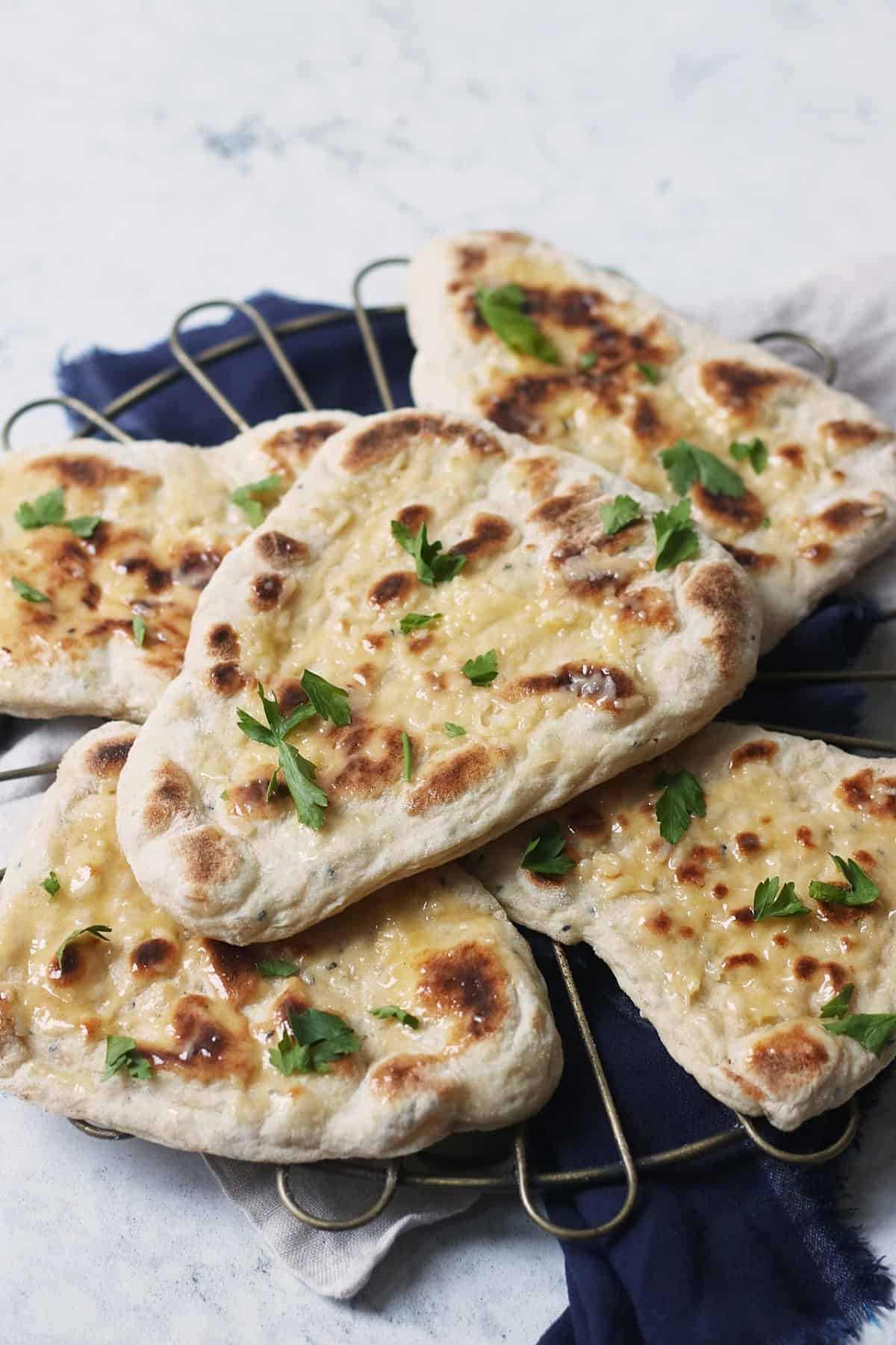 A closeup of one vegan naan bread stacked on top of 4 others a wire rack