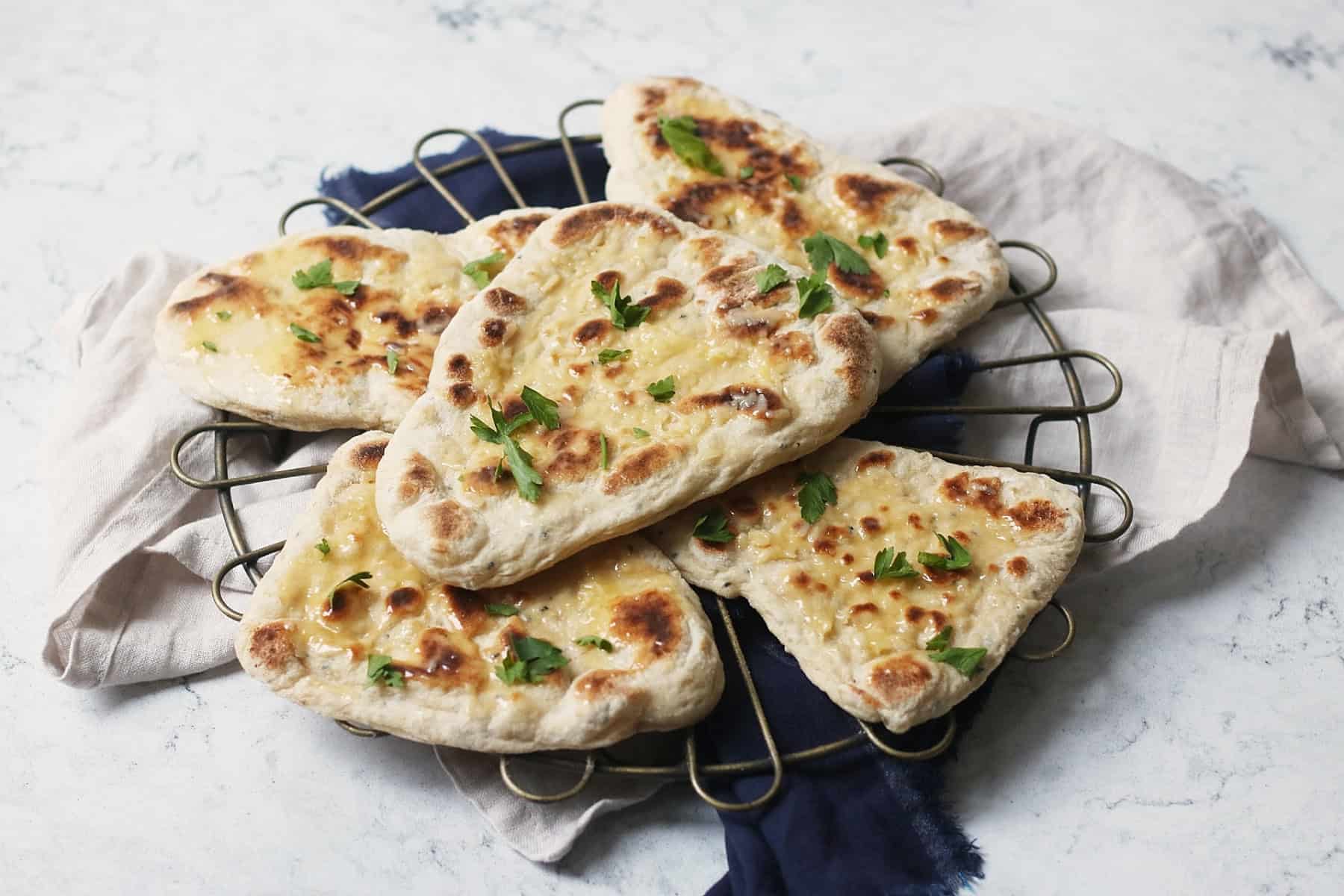 5 vegan naan breads stacked on top of a wire rack