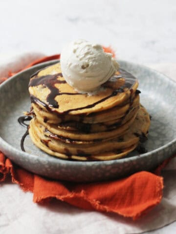 A stack of Vegan Sweet Potato Pancakes with chocolate sauce