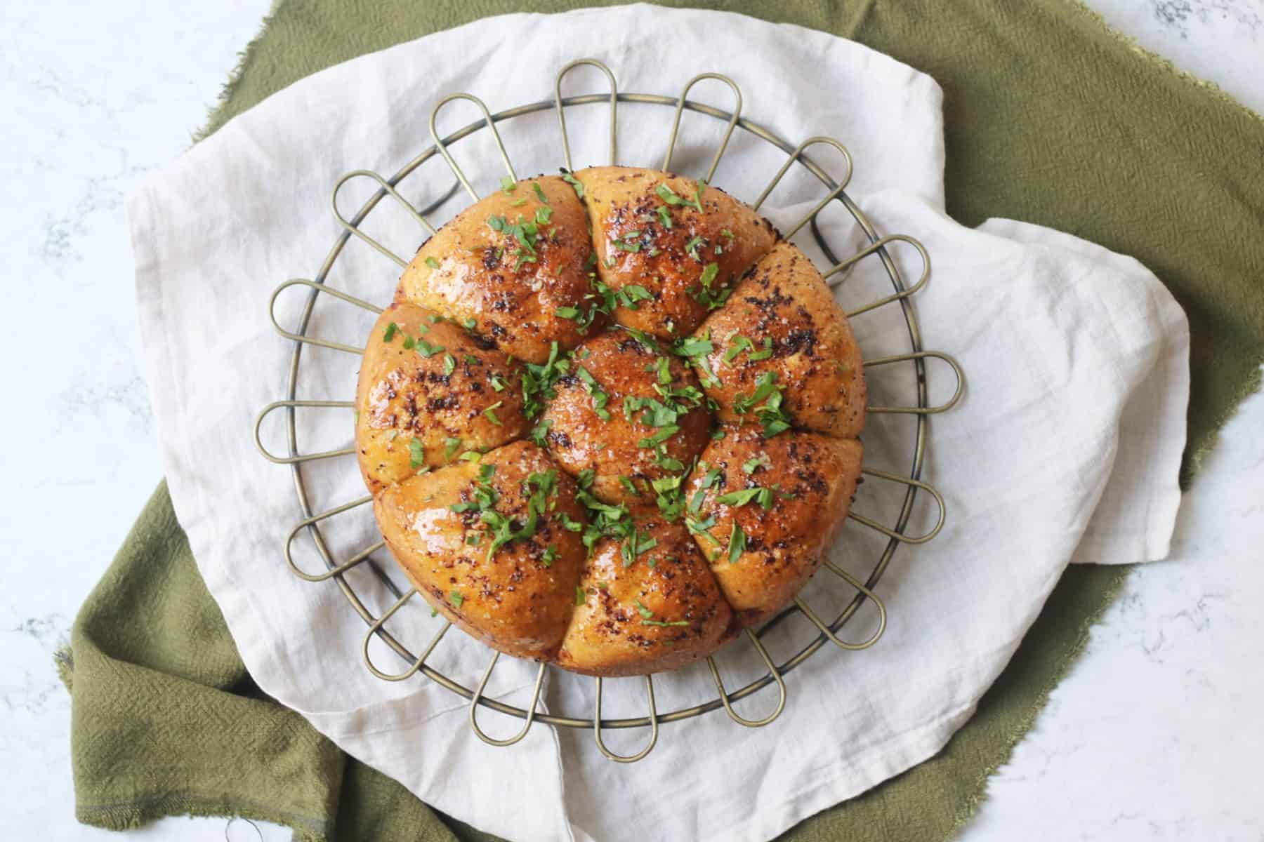 Vegan Tear and Share Garlic Bread on a wire rack and white and green napkins