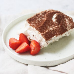 A portion of vegan tiramisu served with fresh strawberries