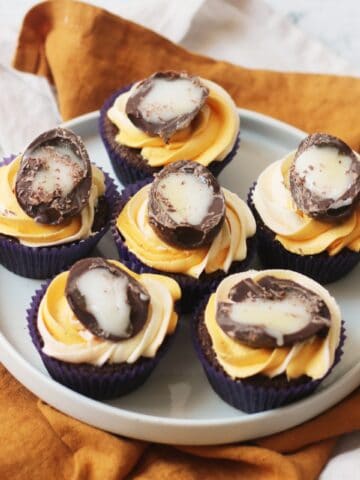 6 Vegan Creme Egg Cupcakes on a white plate