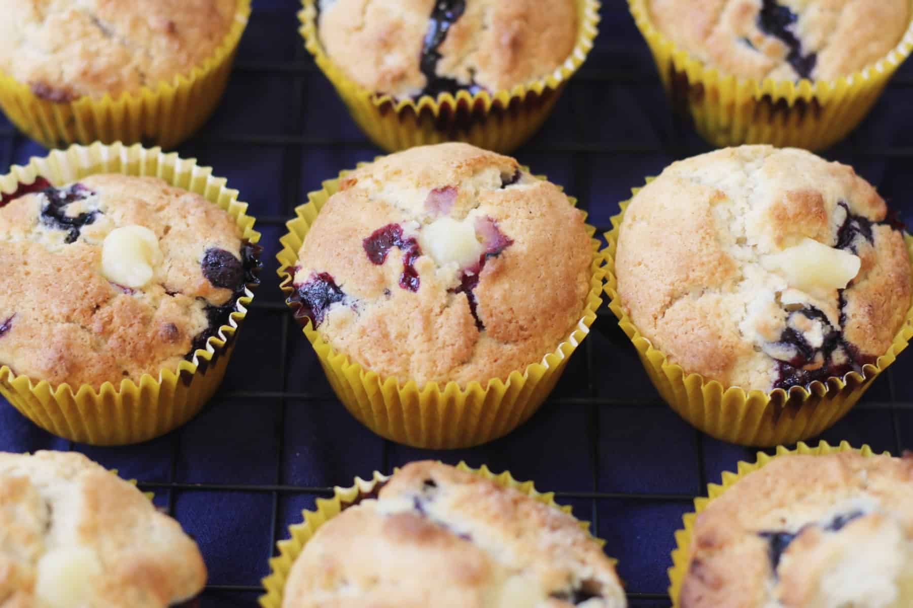 9 Vegan Blueberry and Lemon Curd Stuffed Muffins in yellow paper cases on a wire rack