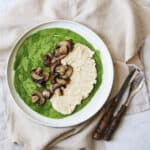 A spinach crêpe on a plate topped with vegan ricotta and cooked mushrooms