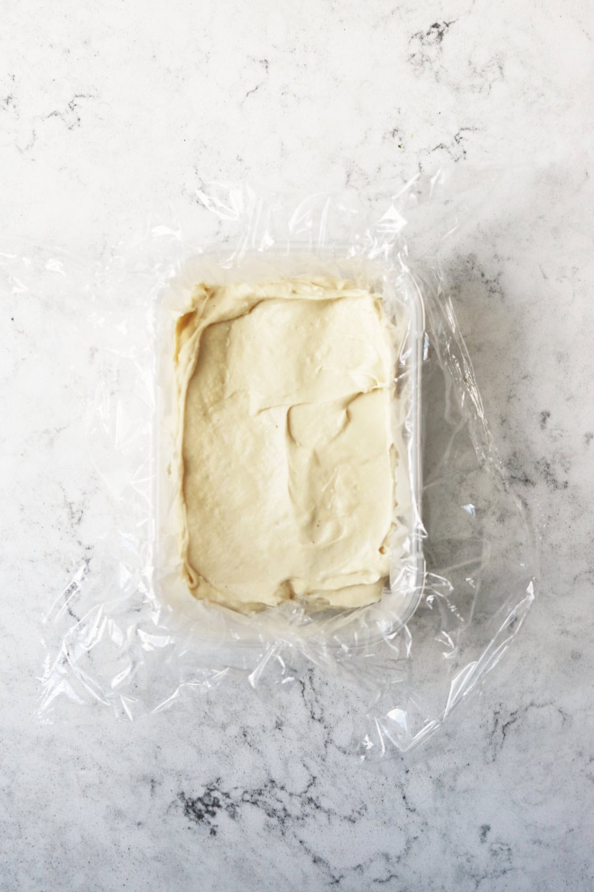 Vegan halloumi setting in a container lined with cling film