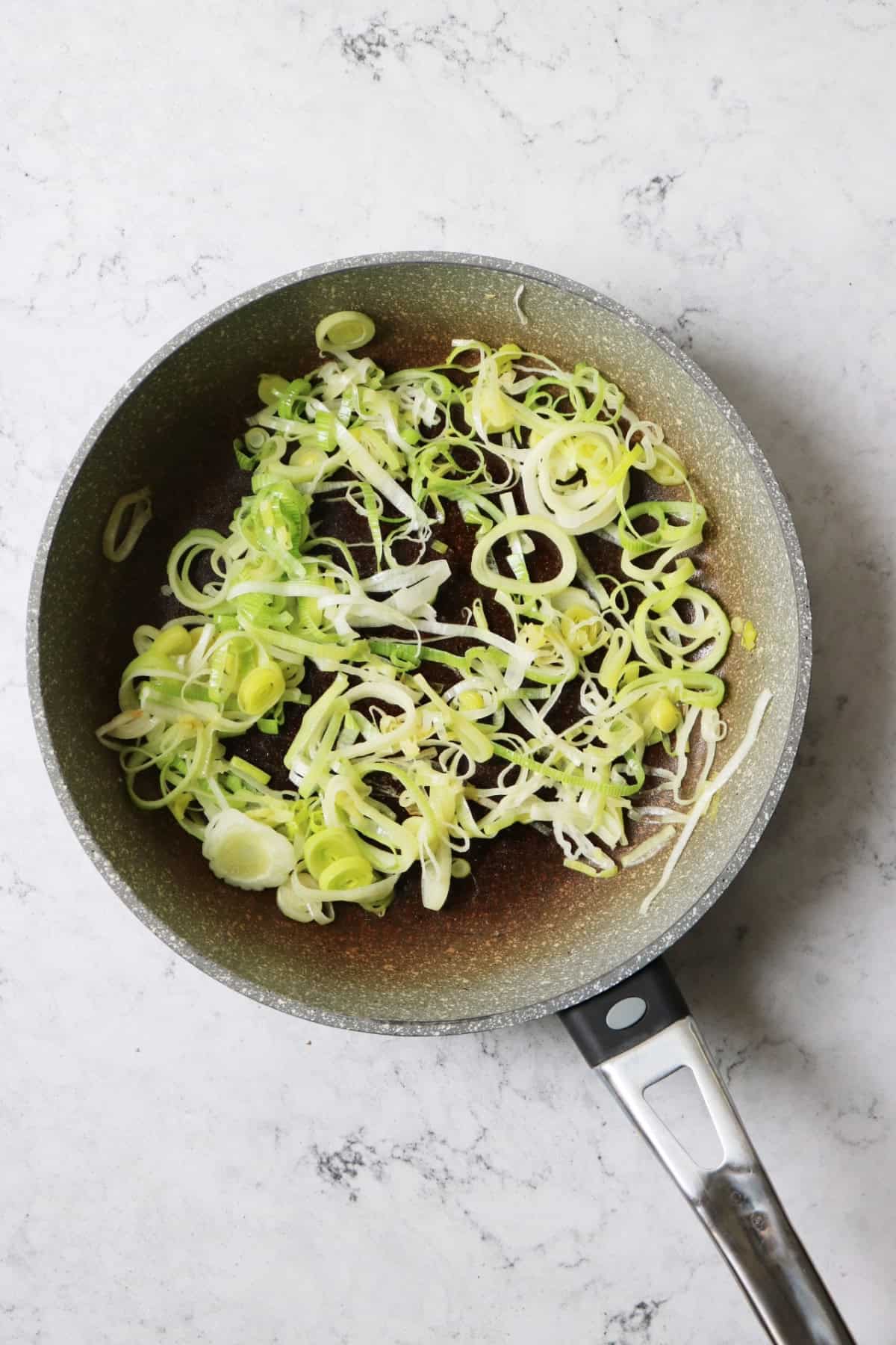 Leeks softening in a frying pan