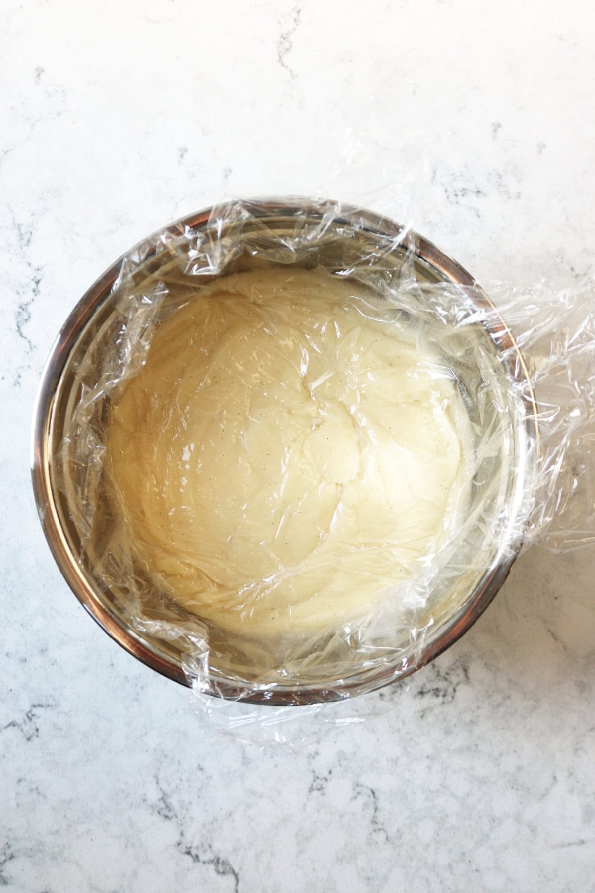 A bowl of vegan creme patissiere with clingfilm over the top.