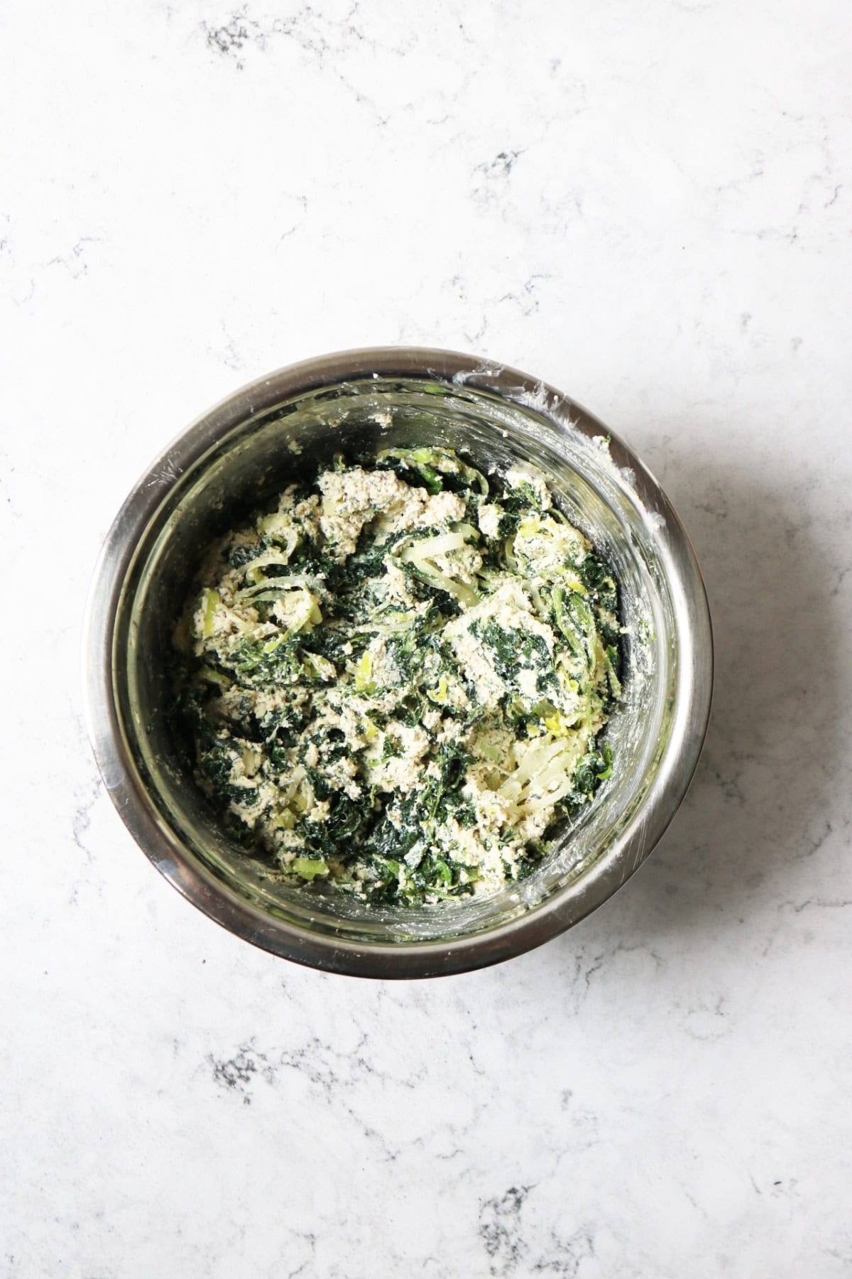 A bowl of vegan spanakopita filling made from vegan ricotta, spinach and leeks