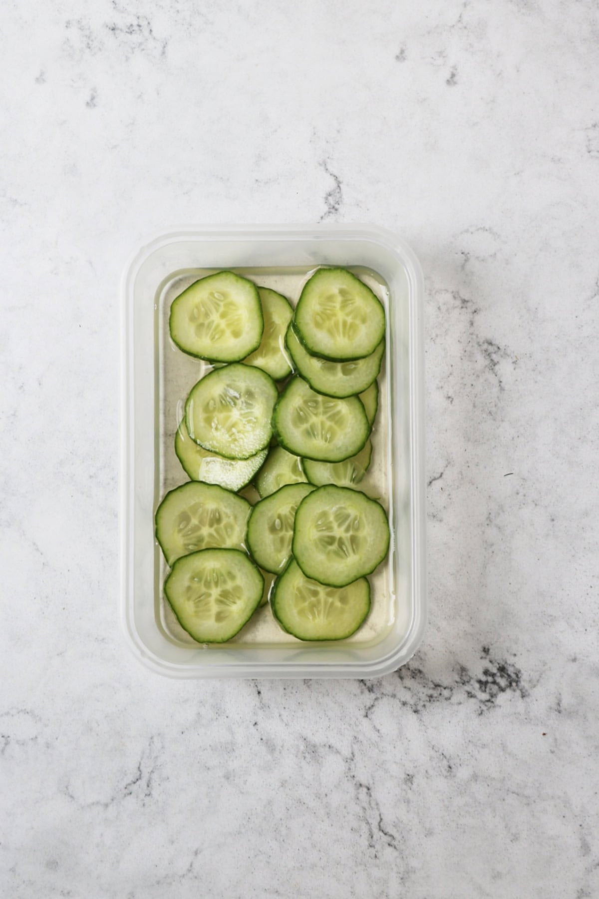 Slices of cucumber pickling in a small dish