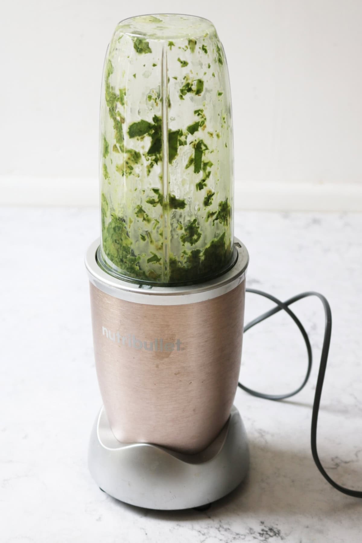 Blending herbs in a nutribullet to make salsa verde