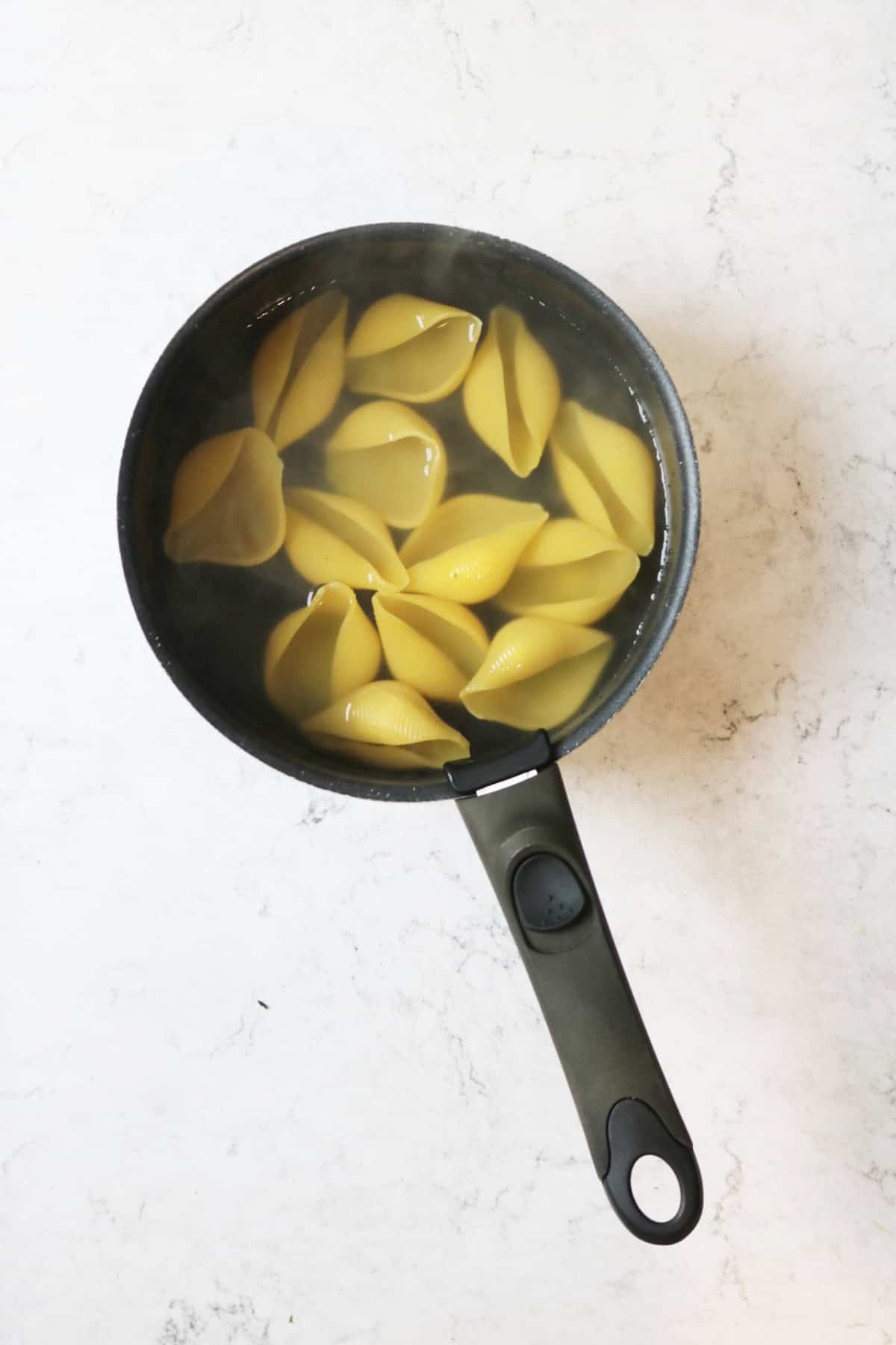 Jumbo pasta shells cooking in a pan of boiling water