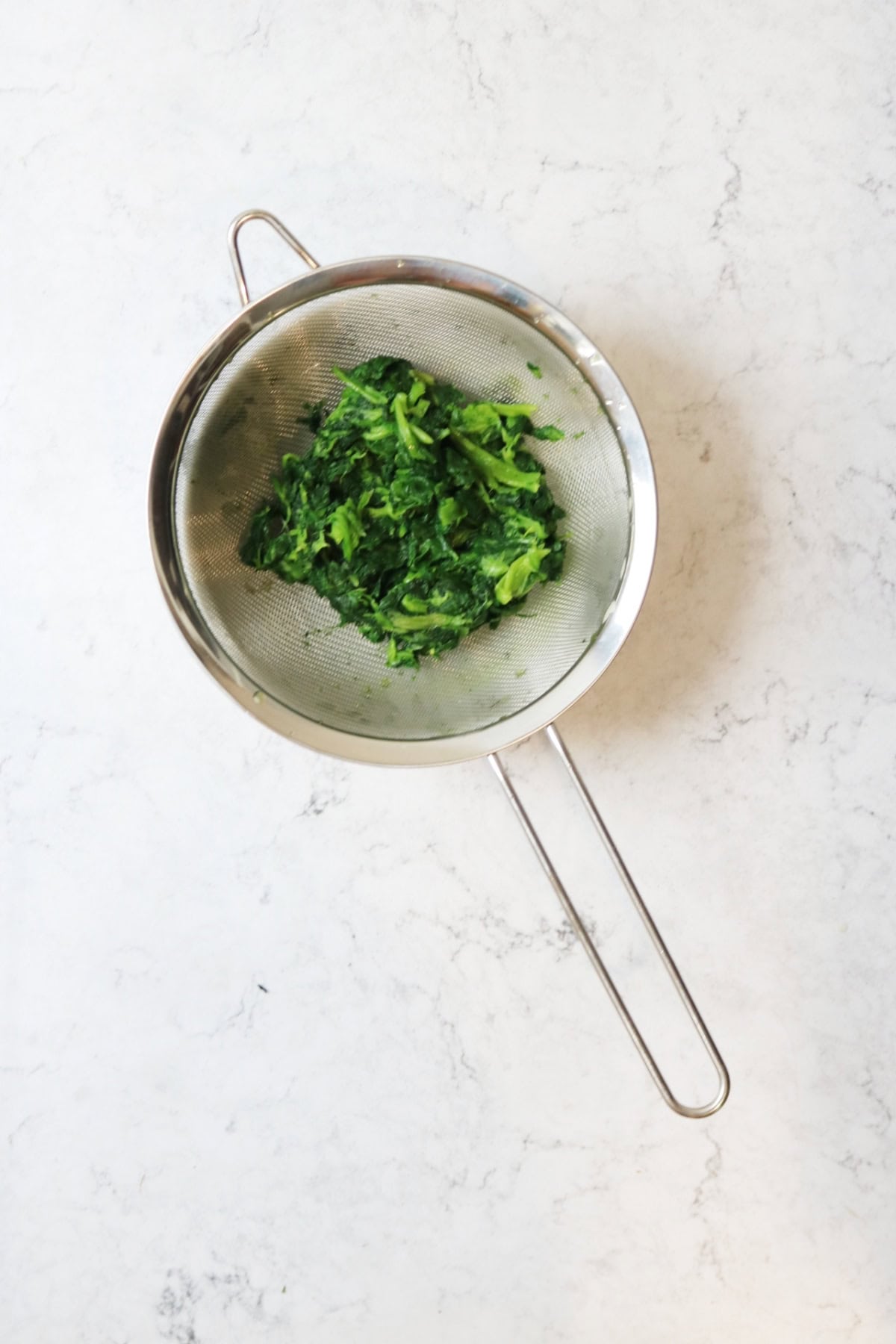 Frozen spinach thawing in a sieve