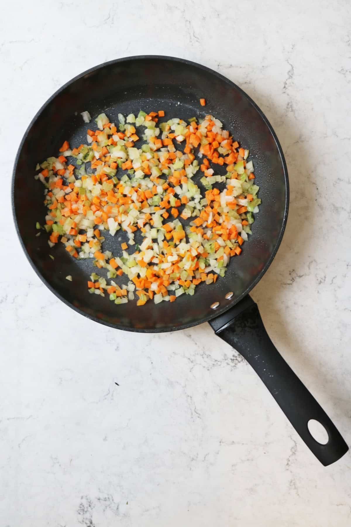 Carrot, onion and celery frying in a pan