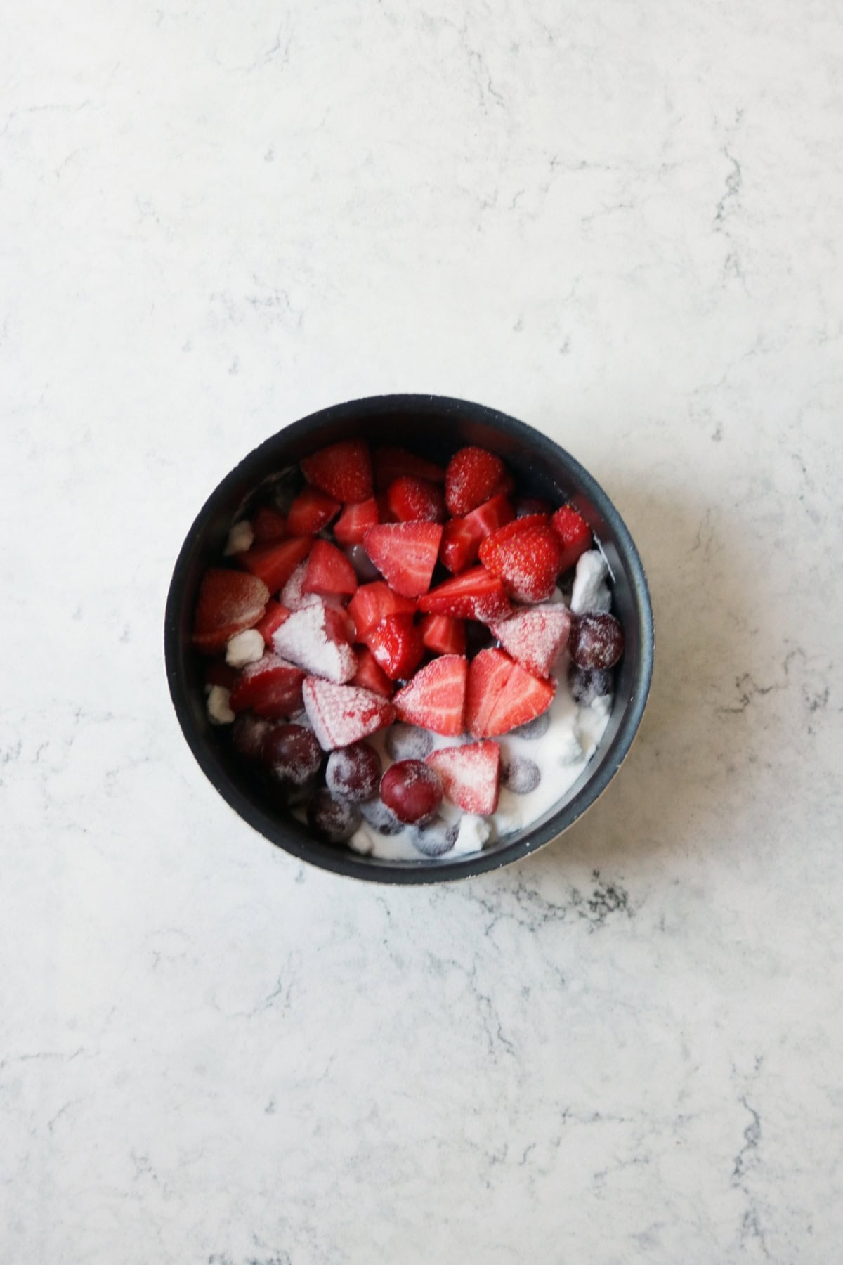 Gooseberries and strawberries with caster sugar in a saucepan