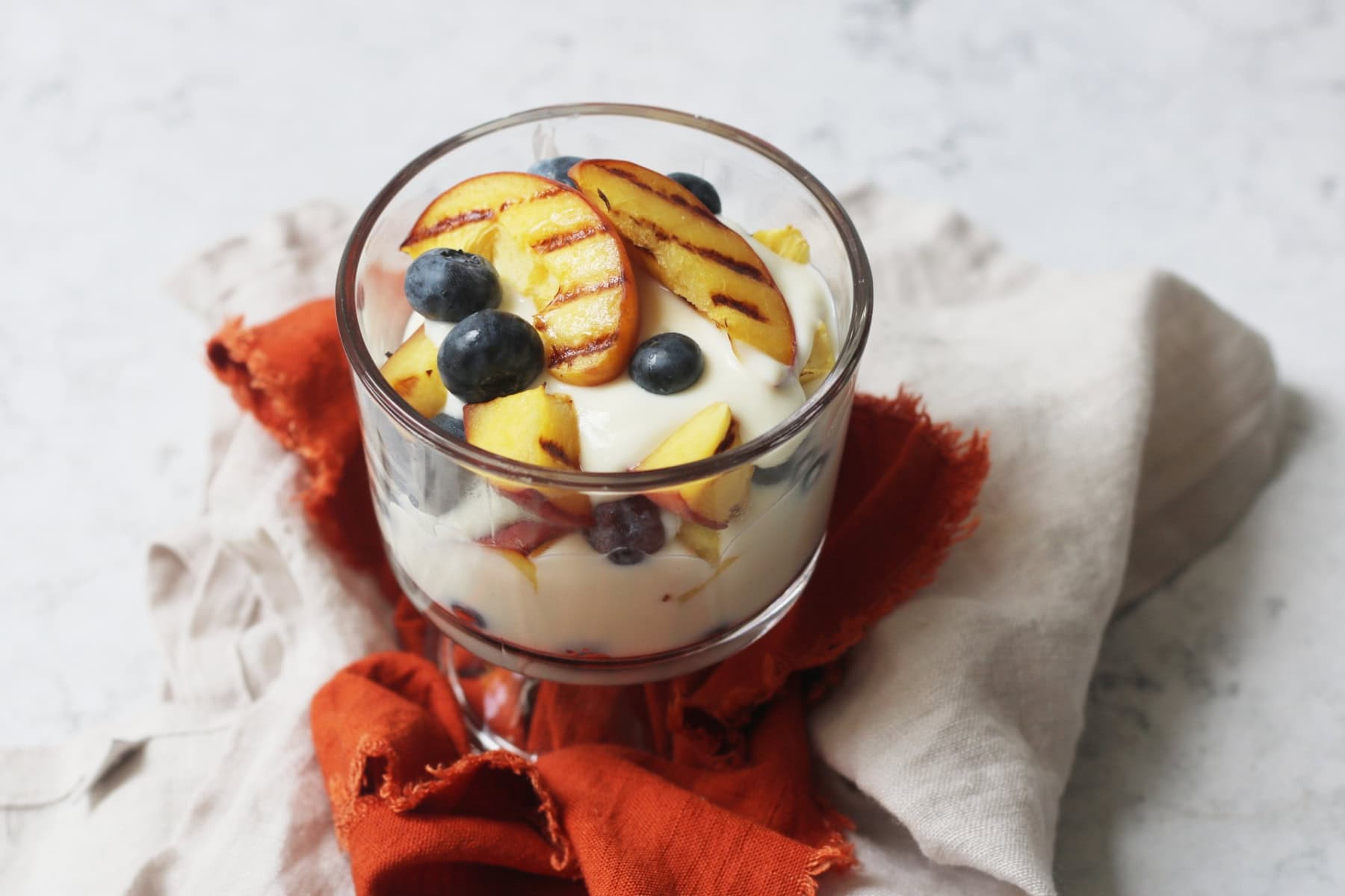 Vegan Grilled Peach and Blueberry Parfait in a glass pudding bowl